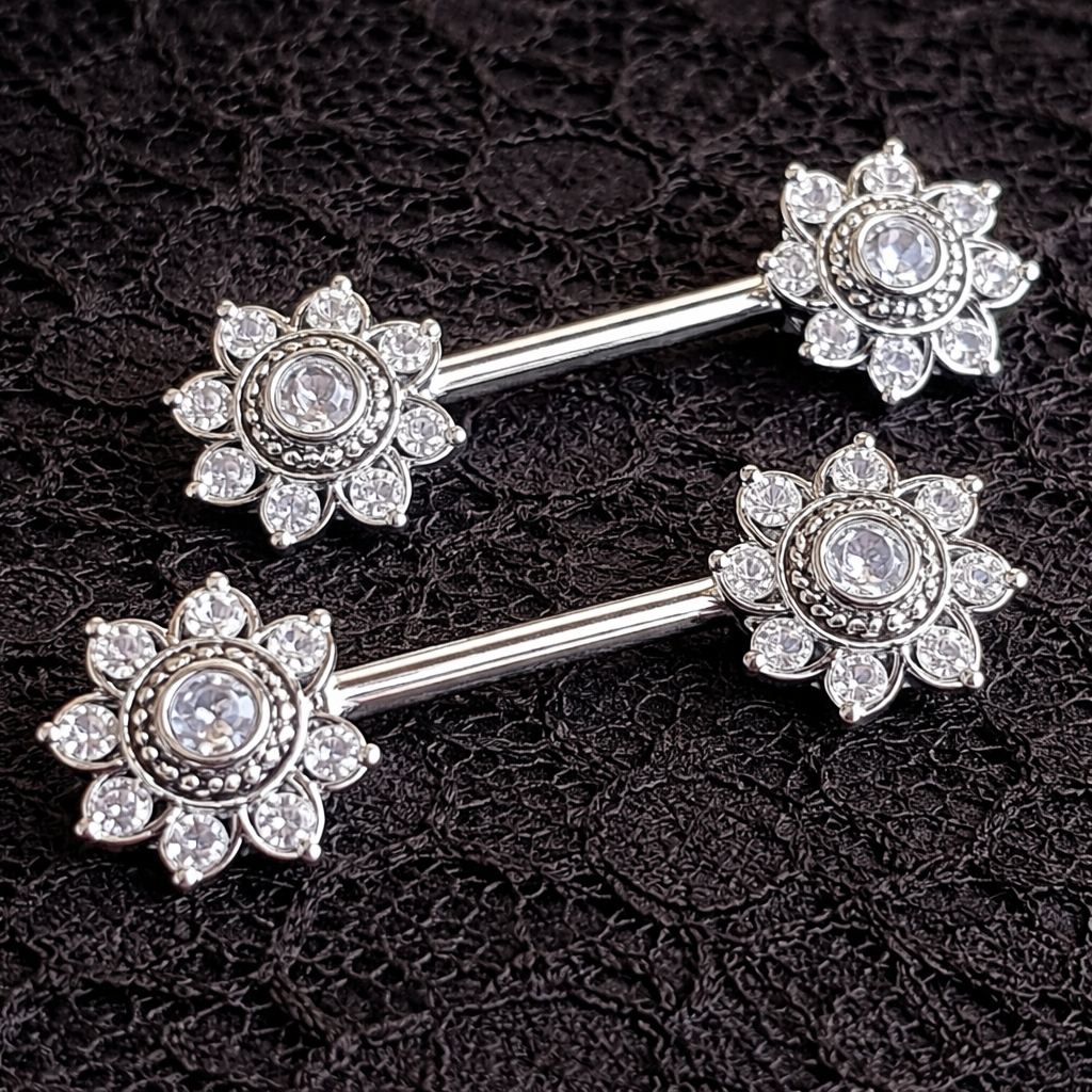Silver mandala nipple bars with floral designs on a black lace background