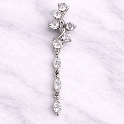 Silver navel ring with clear stones on a white marble background