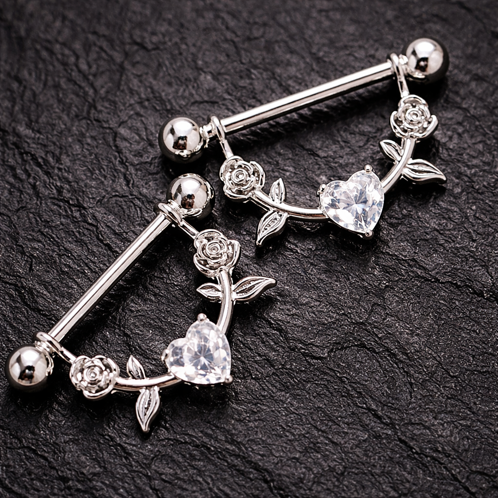 Silver nipple bars with floral and heart designs on a black background