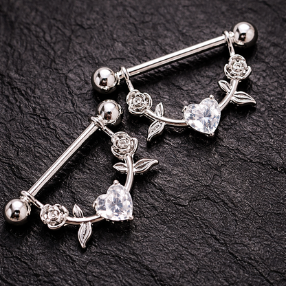 Silver nipple bars with floral and heart designs on a black background