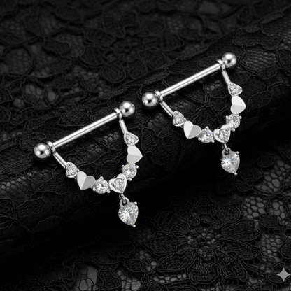 Silver nipple bars with heart-shaped gemstones on a black lace background