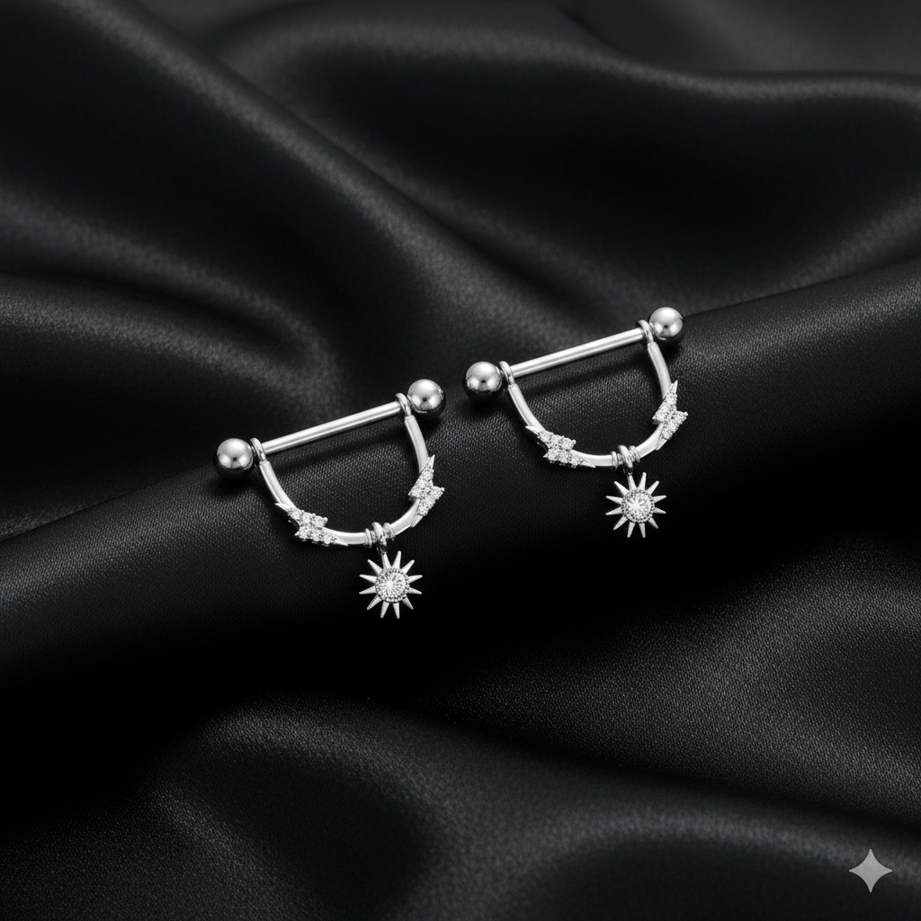 Silver nipple piercing shields with star designs on a black satin background