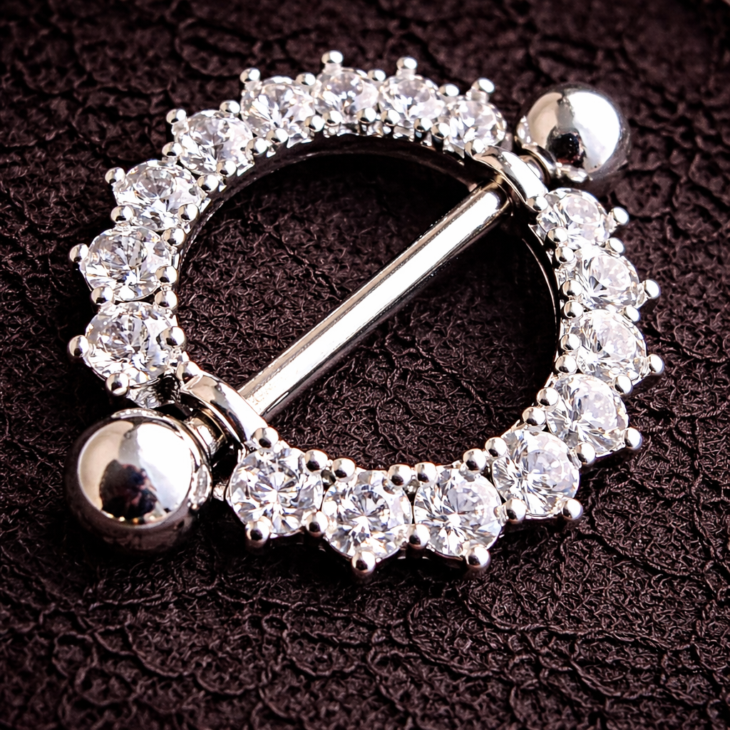 Silver nipple ring with clear gemstones on a dark textured background