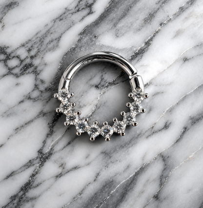 Silver septum ring with clear stones on a marble background