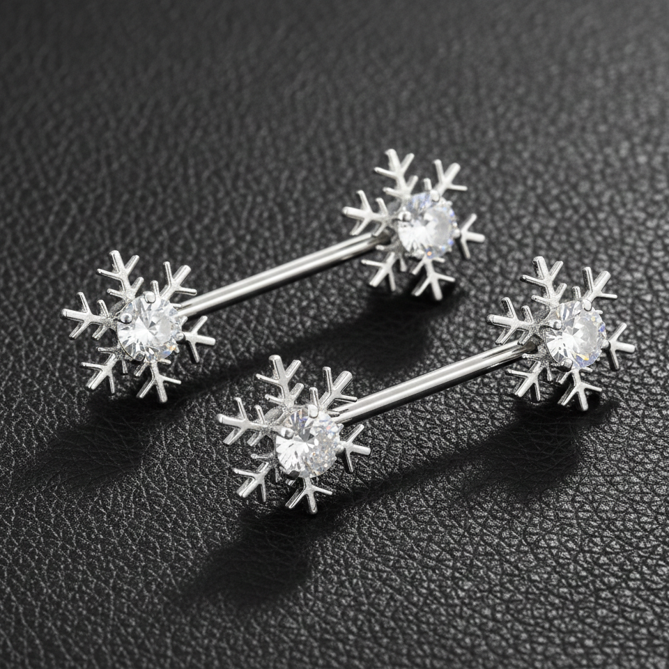 Silver snowflake shaped nipple bars on a dark textured surface