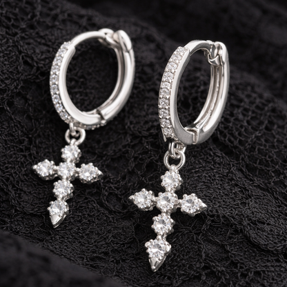 Silver hoop earrings with cross charms on a black textured background