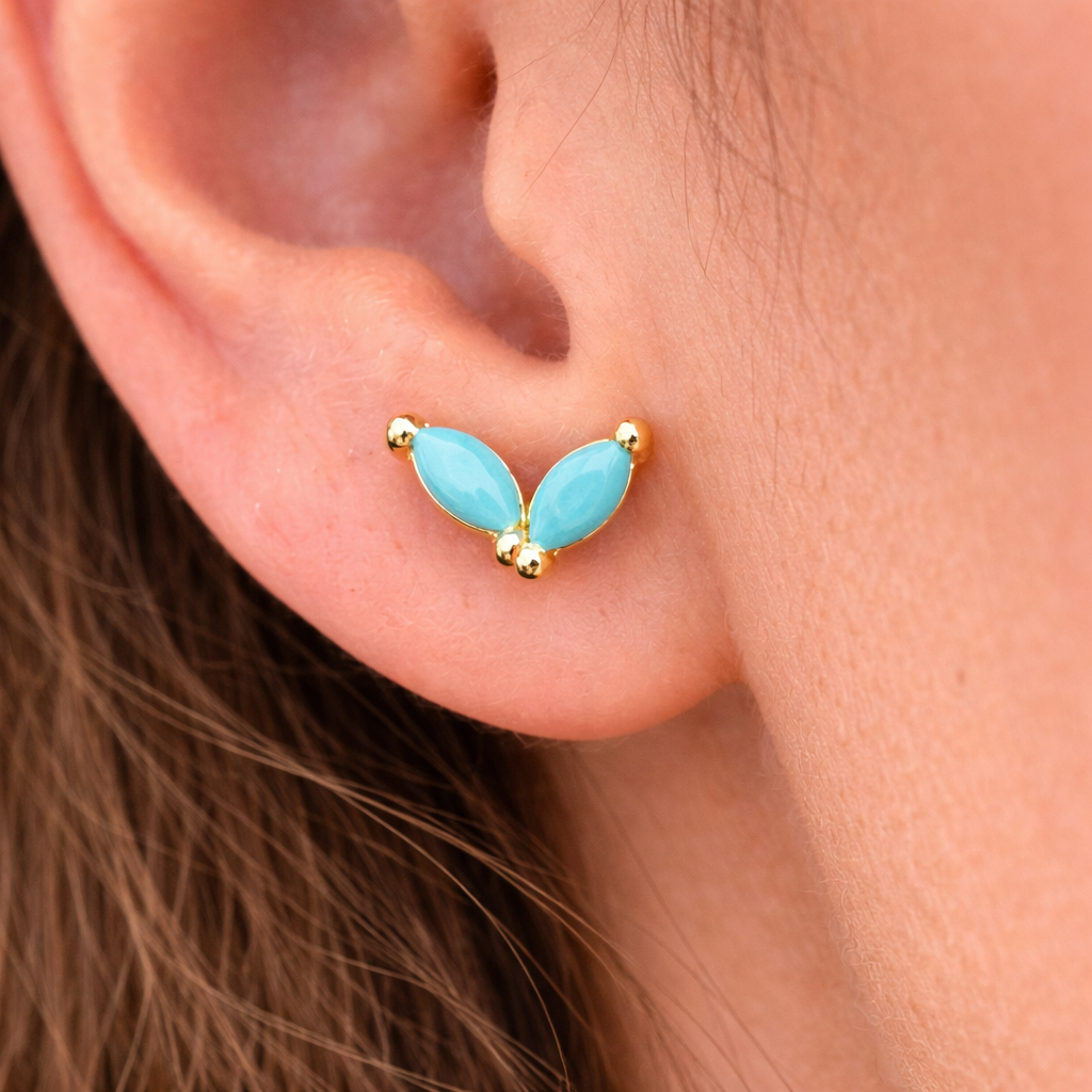 Gold earrings with blue stones worn by a person