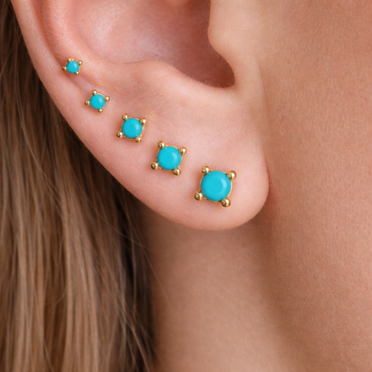 Close-up of turquoise stud earrings on an ear