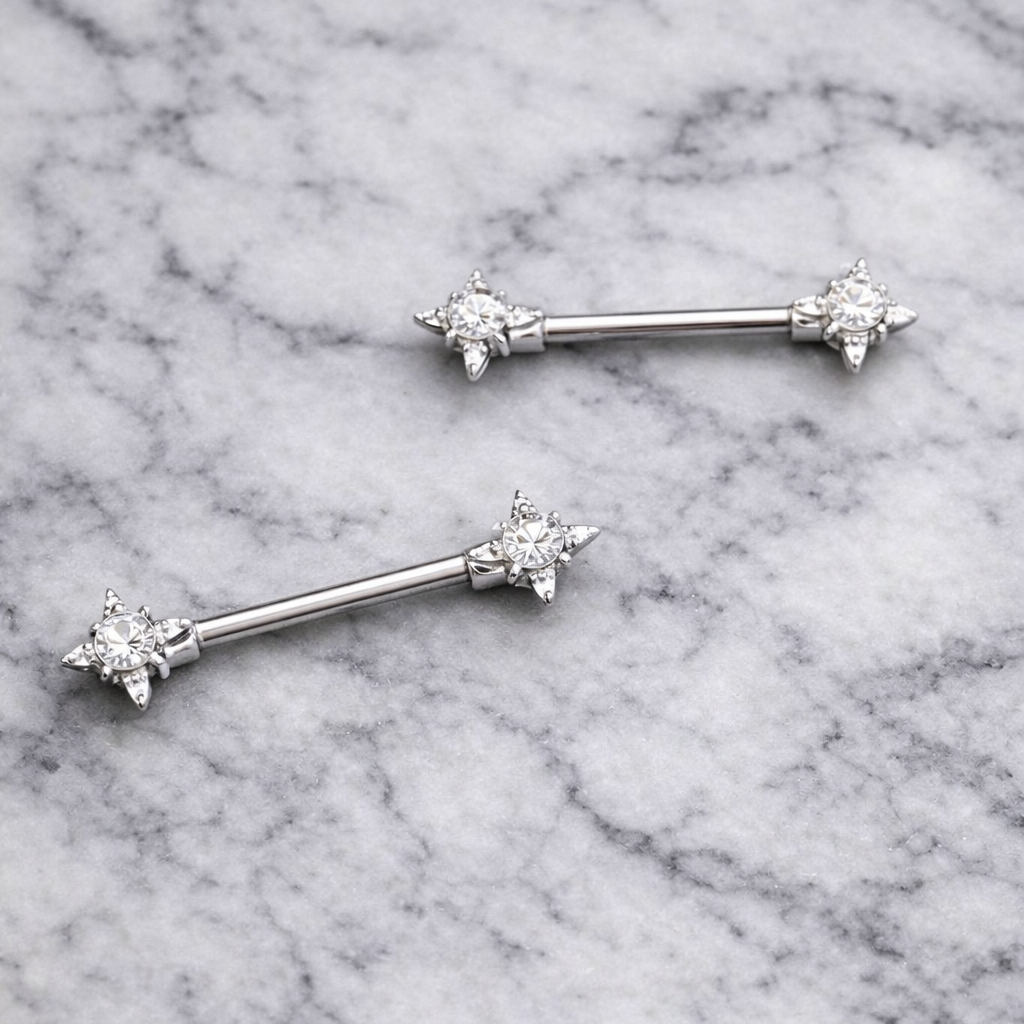 Two nipple silver barbell earrings with star-shaped ends on a marble background