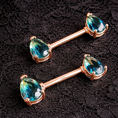 Two rose gold barbell with blue gemstones on a dark textured background