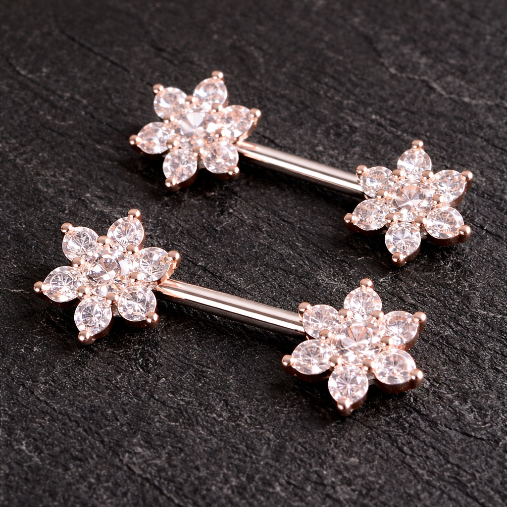 Two rose gold nipple bars with floral designs on a dark surface
