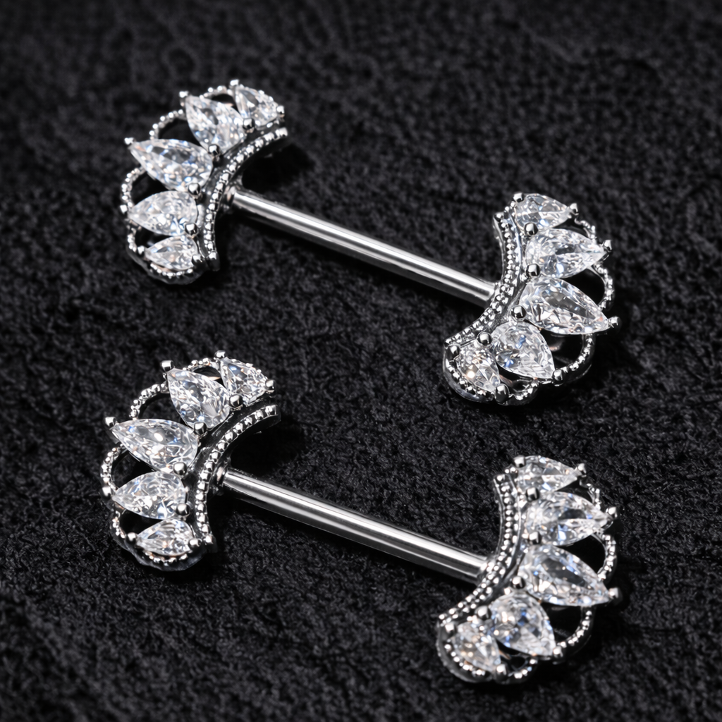 Two silver belly nipple piercing bars with clear gemstones on a black background