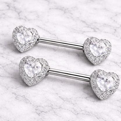 Two silver heart-shaped gemstone nipple barbells on a marble background