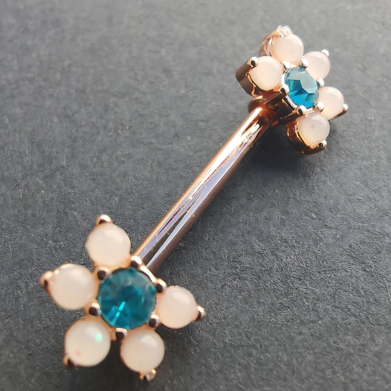 Elegant white flower nipple bar in 14G rose gold surgical steel, featuring a sparkling blue cubic zirconia center.